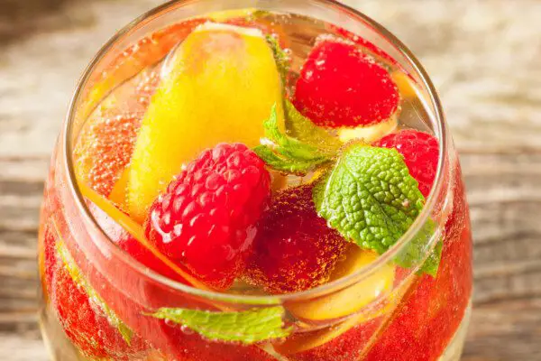 12 Crowd Pleasing Punch Recipes For Your Summer Cookout &Mdash; The Shaken Cocktail White Sangria Punch With White Wine Orange Juice Orange Slices Lime Slices Raspberries And Sparkling Water Cocktail